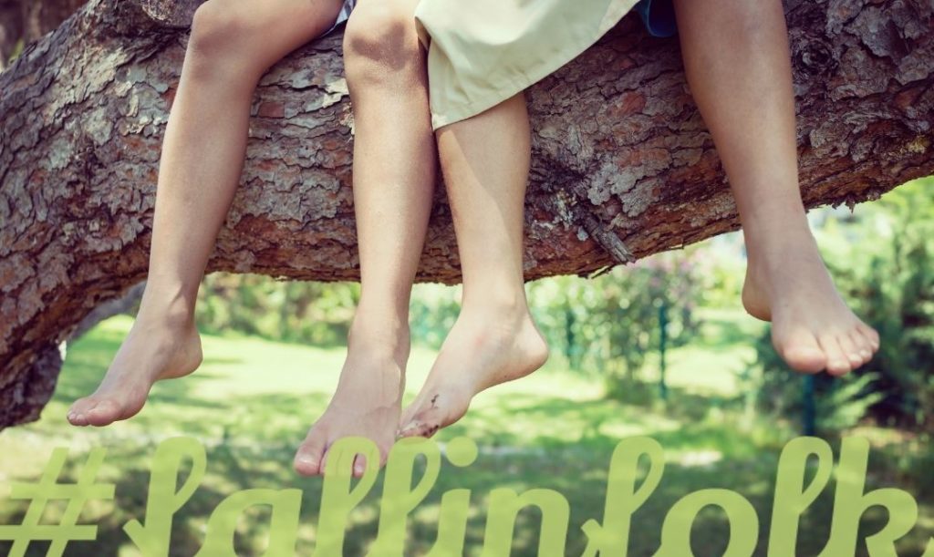 Folk to dzieciństwo. Zdjęcie nóg dzieci siedzących na drzewie. Napis fallinfolk.
