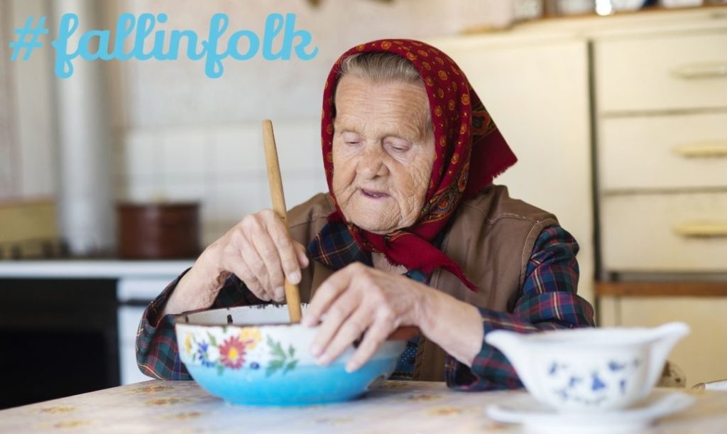 Folk to wspomnienia. Zdjęcie starej babci w chustce na głowie, mieszającej w miskach mąkę. Napis fallinfolk.