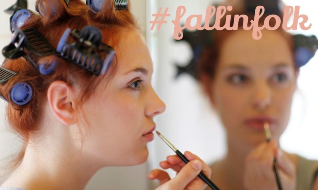 Sprzężenie zwrotne. Malująca usta kobieta przed lustrem z wałkami na włosach. Napis fallinfolk.