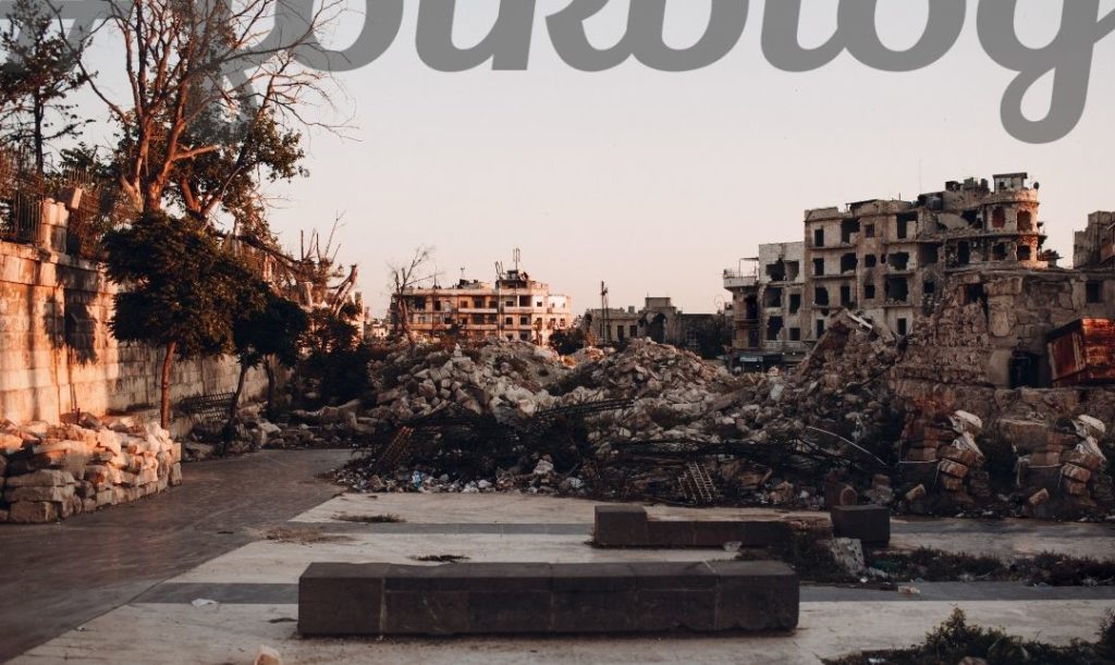 Doświadczenie nieprzekazywalne. Obraz zniszczeń wojennych, gruzy w mieście. Napis folkblog.